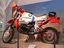 Race-prepared R 80 G/S motorcycle, with Paris Dakar, Elf, and Playboy stickers. Displayed on a stand in a museum