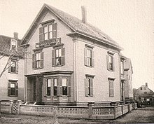 white wood three-storey house surrounded by picket fence