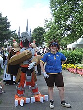 Photo d'un cosplay : à droite, une personne avec un haut bleu et un short marron, à gauche, une personne déguisée en androïde.