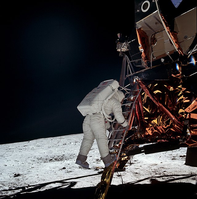 Buzz Aldrin exiting the lunar lander and stepping onto the moon. The photo was taken by Neil Armstrong, who had just exited the same lander.