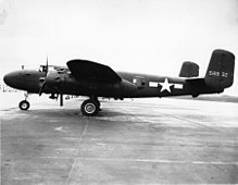 Черно-белое фото первого бомбардировщика, припаркованного перпендикулярно камере, лицом влево, сзади крыла - звезда перед горизонтальными полосами.