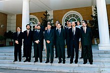 Groupe d'hommes et de femmes réunis devant un bâtiment public pour une photo officielle.