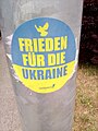 Aufkleber am Laternenmast in ukrainischen Farben mit Aufschrift Frieden für die Ukraine