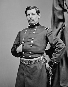 Man with mustache and military uniform, striking a Napoleon pose
