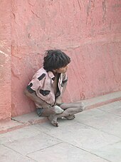 a poor boy sitting in the streets of Mumbai