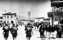 Italian soldiers in an unidentified location in Albania, April 12, 1939. Italian soldiers passing Albanians, 7 April 1939.png