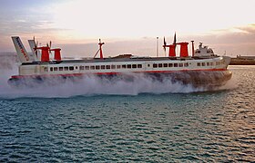 "Un hovercraft se déplace sur une mer calme, au couché du soleil"