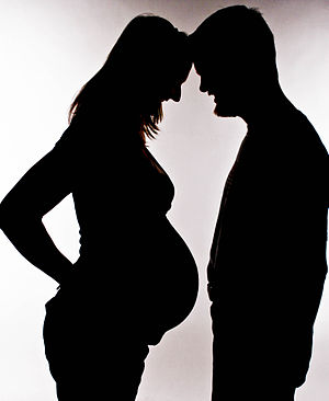 Silhouette or a pregnant woman and her partner...
