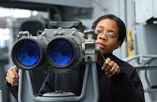 US Naval ship 'Big eyes' 20x120 binoculars in fixed mounting US Navy 021206-N-1328C-501 Signalman 3rd Class Tiffany Culereth from Bronx, N.Y., observes ships in the area through binoculars called "Big Eyes.".jpg
