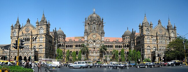 A brown building with clock towers, domes and pyramidal tops. Also a busiest railway station in India.[324] A wide street in front of it
