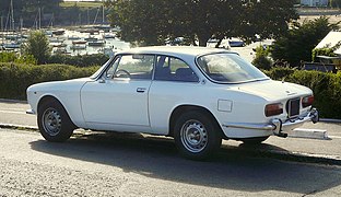 Une Alfa Romeo Giulia GT 2000 (coupé Bertone) vue de ¾ arrière, sur la côte d'Émeraude en Bretagne.