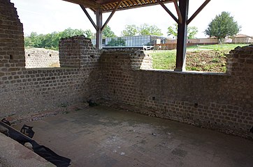 Alveus (petit bassin) jouxtant le côté sud du frigidarium (salle froide) du coin sud-est, et en arrière-plan le nouveau bâtiment d'accueil du site. Le natatio ou piscine froide attenant se trouve derrière le mur de gauche[1].