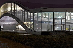 photographie nocturne, d’un couloir vitré éclairé aux formes courbes