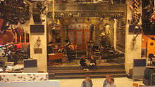Studio 8H in the GE Building at 30 Rockefeller Plaza is where Saturday Night Live (SNL) is filmed and was used as the location for "Live from Studio 6H". 30 Rock is loosely based on creator Tina Fey's experience on that program and several SNL alumni participated in the filming of this episode. SNL stage.jpg