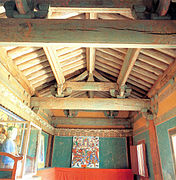 Photographie de l'intérieur d'un temple, l'intérieur de la toiture est visible dans la partie supérieure de la photographie, et dans la partie inférieure les murs d'une salle sont dotées de peintures.