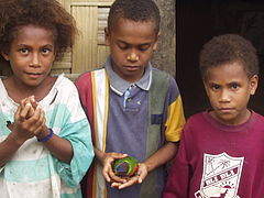 Photographie représentant trois enfants, dont un garçon tenant un perroquet.