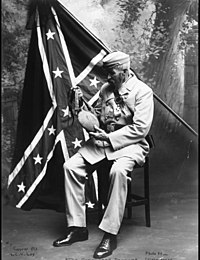 Confederate soldier posing in front of official Confederate battle flag
