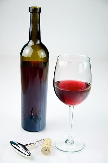 English: Glass of Red Wine with a bottle of Re...