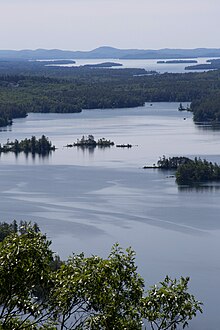 Scenic birds eye view of squam lake looking over green trees and mountain horizon.