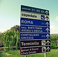 Road signs in Italy use a variation of the typeface called Alfabeto normale, or the condensed form of it, called Alfabeto stretto (the latter is the one on the top and the bottom signs in the photo).