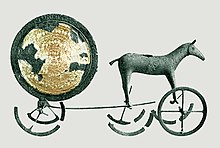 char sous forme d'une boule dorée agrémenté de fragments de roue et d'un cheval en bronze