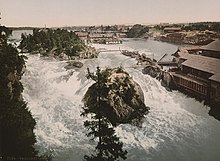 Une photo historique d'une grande cascade entourée de bâtiments industriels.
