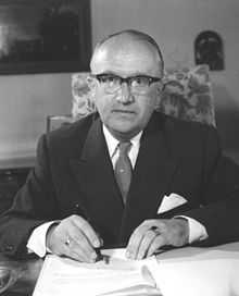 Photograph of bespectacled Hallstein sitting at desk, writing