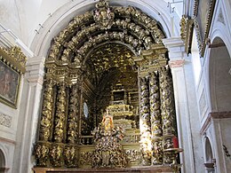 Photographie couleur d'un retable monumental doré à colonnes clôturant un chœur d'église.