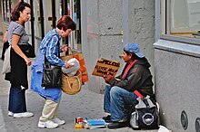 A woman giving a homeless man food in New York City, United States (2008) Helping the homeless.jpg