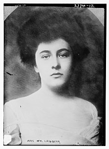 A black-and-white photograph of a white woman with dark hair in a bouffant updo, from the 1910s
