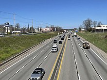 Straight, heavily-traveled section of six-lane highway in suburban area