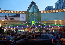 An illuminated low-rise glass building with cars in the front