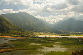 Oligyrtos-Massiv, 100 % Wald; Hochwasser: grünes Schilf, nasse Felder