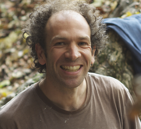 Portrait d'un homme quarantenaire, souriant, au front dégarni, vêtu d'un teeshirt.