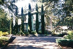 Photograph of a large house partially obscured by trees