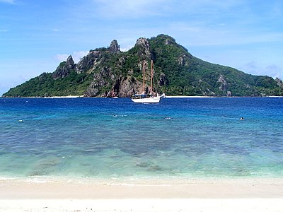 Photograph of a sailboat moored in front of a mountainous island in Fiji