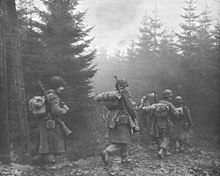 Men of the 325th Glider Infantry Regiment moving through fog to a new position, Belgium, December 1944. TROOPS OF 325TH GLIDER INFANTRY MOVING THROUGH FOG TO A NEW POSITION.jpg