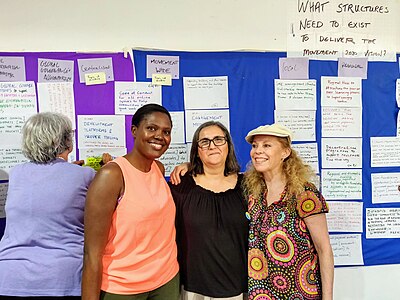 Three people in front of a wall covered with notes.