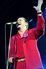 A man in a red shirt singing into a microphone