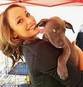 A smiling Kaci, holding a puppy