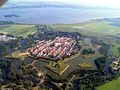 Luftfoto af den befæstede by Naarden. Den stjerneformede jordfæstning er planlagt i den tidlige krudtalder til at holde fjenden på afstand af byen, for derved at beskytte den mod beskydning.