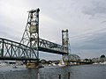 A sailboat passes beneath the open lift span