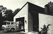 A one-bay firehouse with a white firetruck exiting
