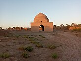 A photo of a small mosque surrounded by desert