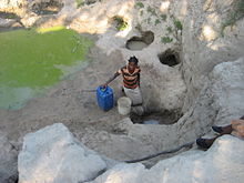 Woman fetching water during the dry season from a polluted source in Machaze District of the Central Manica Province Daily struggle for water (5400691444).jpg