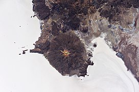 Salar de Uyuni set fra rummet med vulkanen Tunupa i midten. Rester efter en kyst er synlig i saltformationerne (nederst til højre)