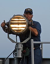 A United States Navy sailor sending Morse code using a signal lamp Seaman send Morse code signals.jpg