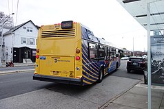 The rear of a Nova LFS bus in Q46 service on a large road in Hillcrest, Queens, during the autumn