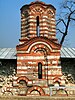 frontal view of a partially destroyed medieval church constructed out of interchanging rows of stone and red brick