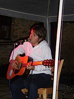 A man sits on a chair playing a guitar